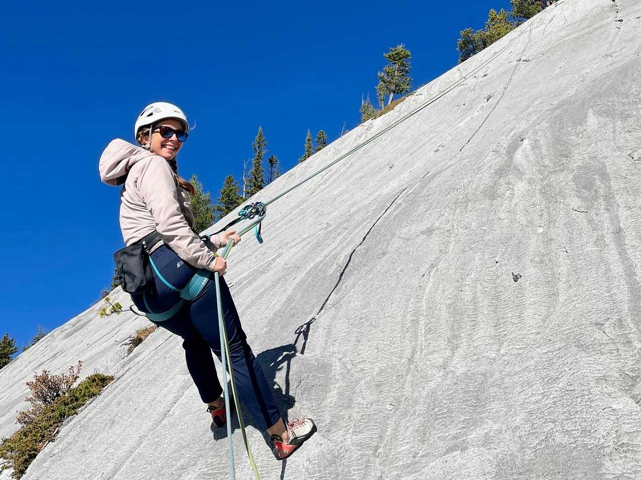 Woman repelling down a mountain face in the alberta rockies