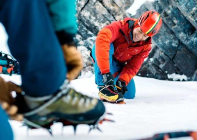 Closeup of a man putting on ice crampons, getting ready to climb a frozen waterfall in Nordegg, Alberta