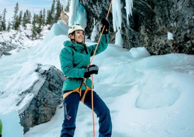 Woman belaying a climber ice climbing in the David Thompson Corridor, near Nordegg Alberta