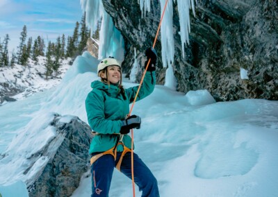 Woman belaying a climber ice climbing in the David Thompson Corridor, near Nordegg Alberta