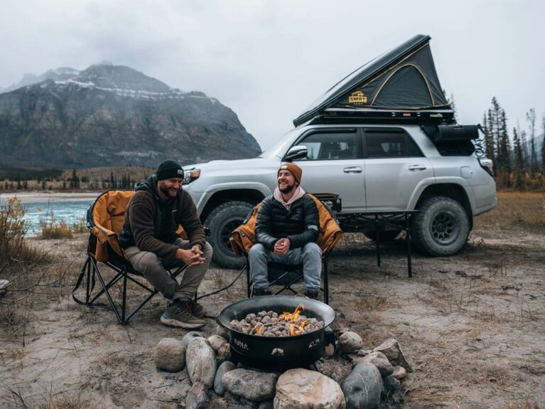 Two friends car camping with a propane fire in the mist in David Thompson Country, Alberta