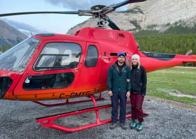 A young Couple posing beside a helicopter after a successful alpine tour