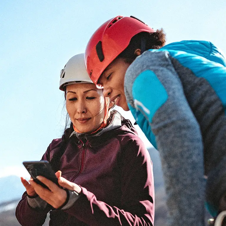 Two female climbers looking at a smart phone