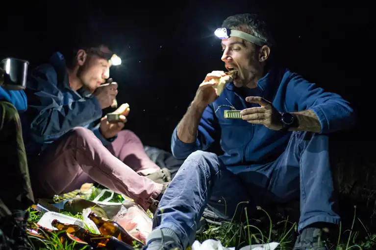 Climbers eating by headlamp